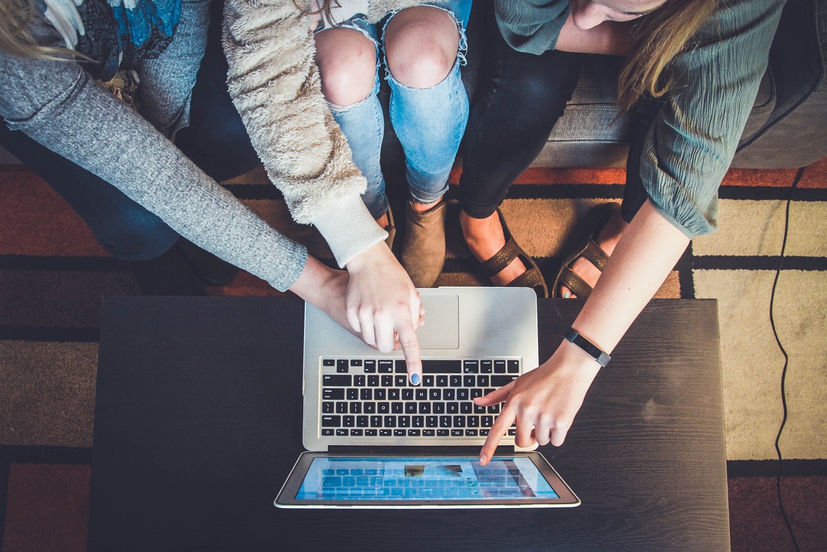 Three students pointing at an online class