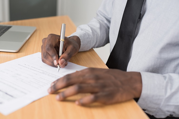 Man writing on paper at an office desk